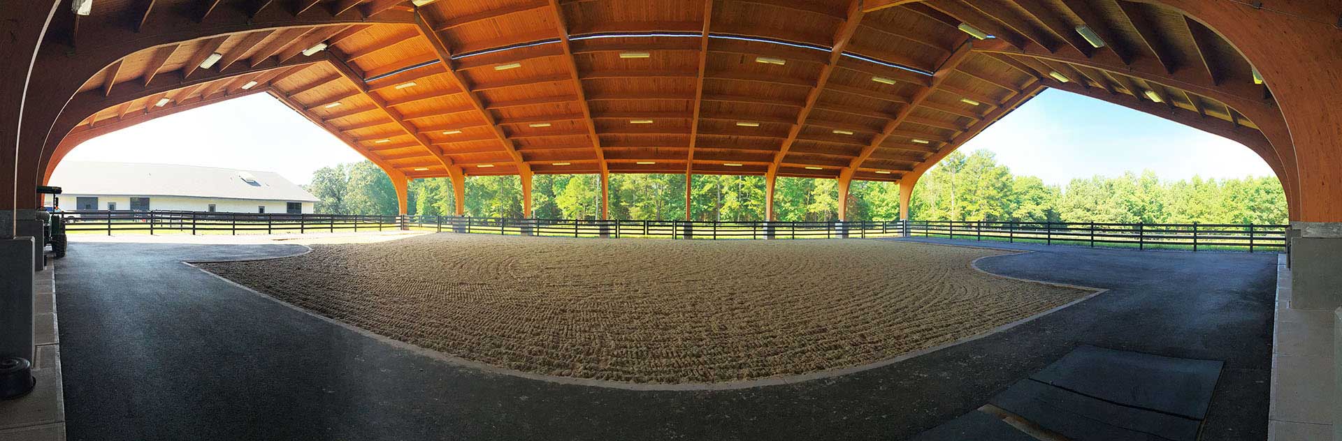 A large empty riding arena with a carpet on the ground.